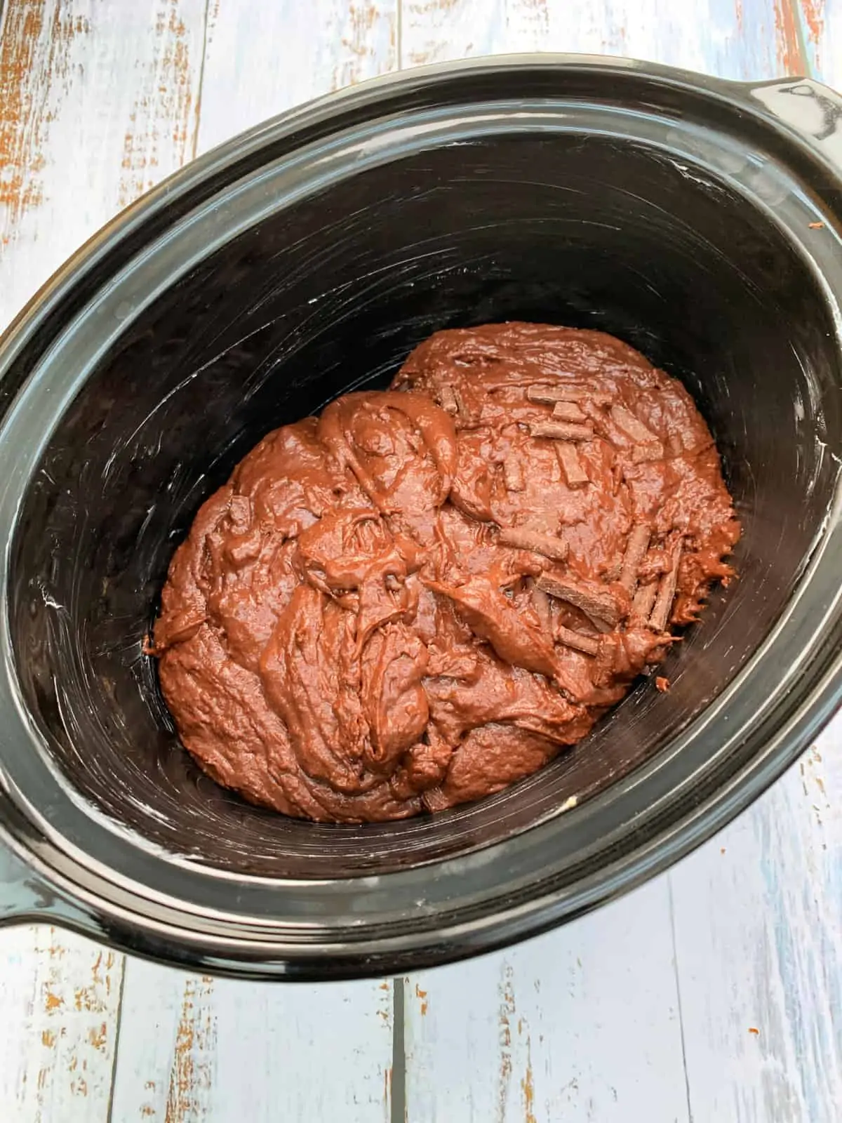 Slow cooker pot with chocolate cake mixture in it.