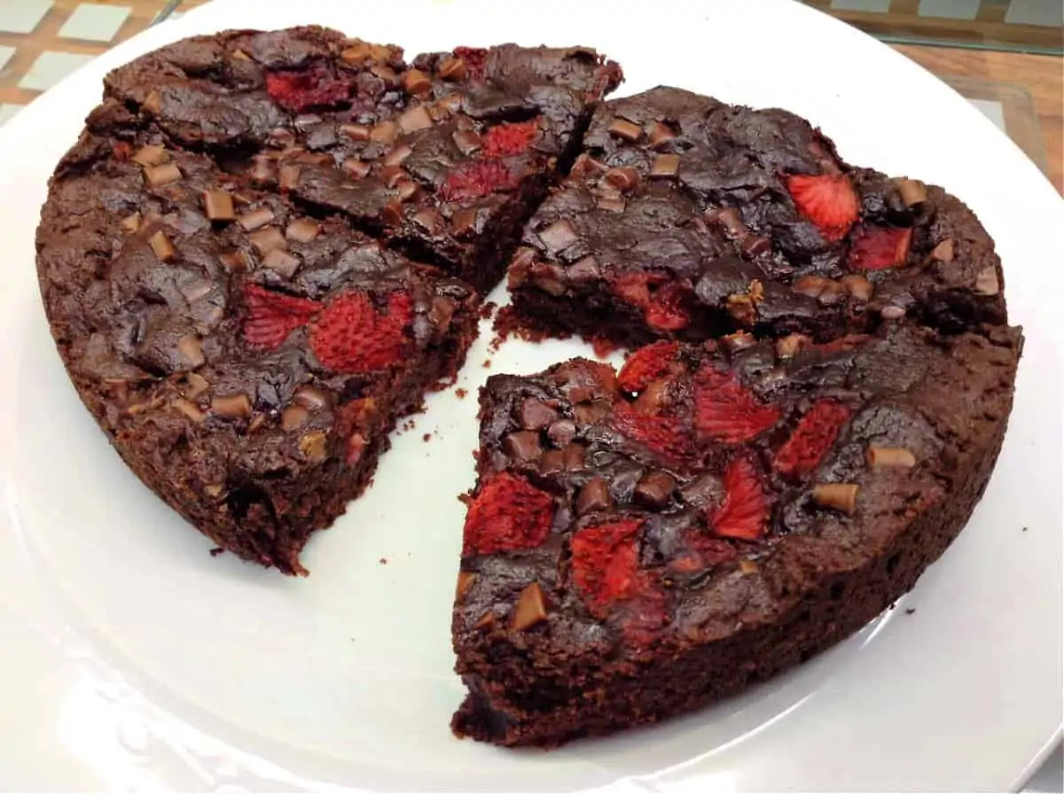 Double chocolate cookie with strawberries on a white plate, cut into 4.