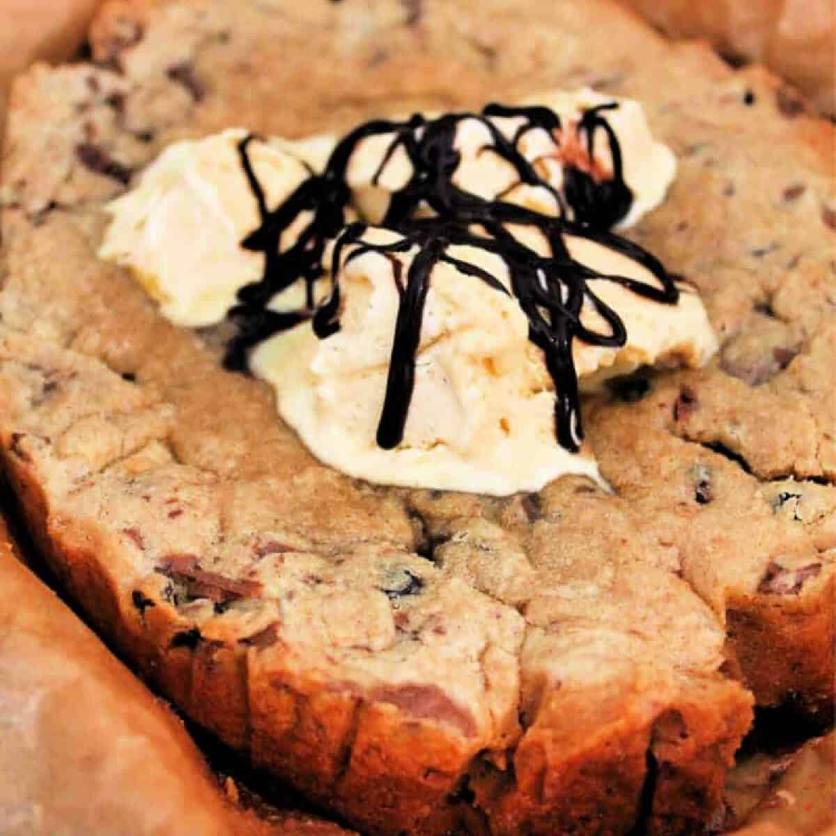 Giant choc chip cookie served with vanilla ice cream and drizzles of chocolate sauce.