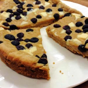 Giant cookie cut into pieces on a white plate.