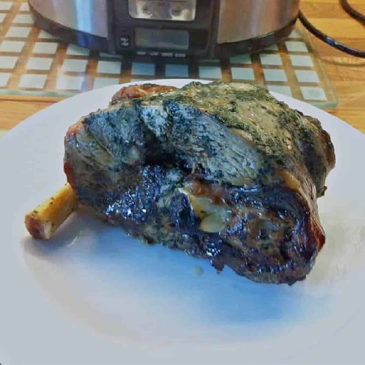 A cooked leg of lamb on a white plate.