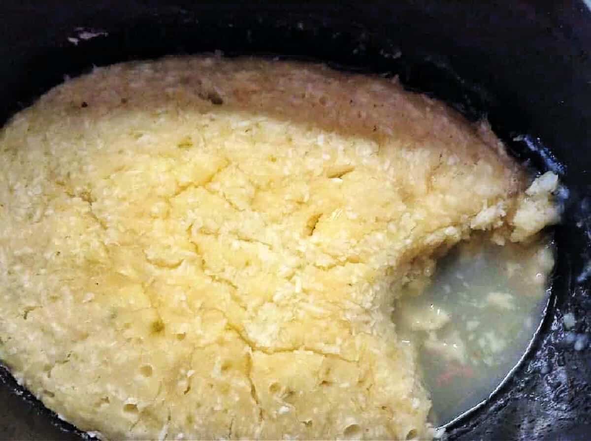 Coconut lime sponge pudding with sauce in slow cooker pot.