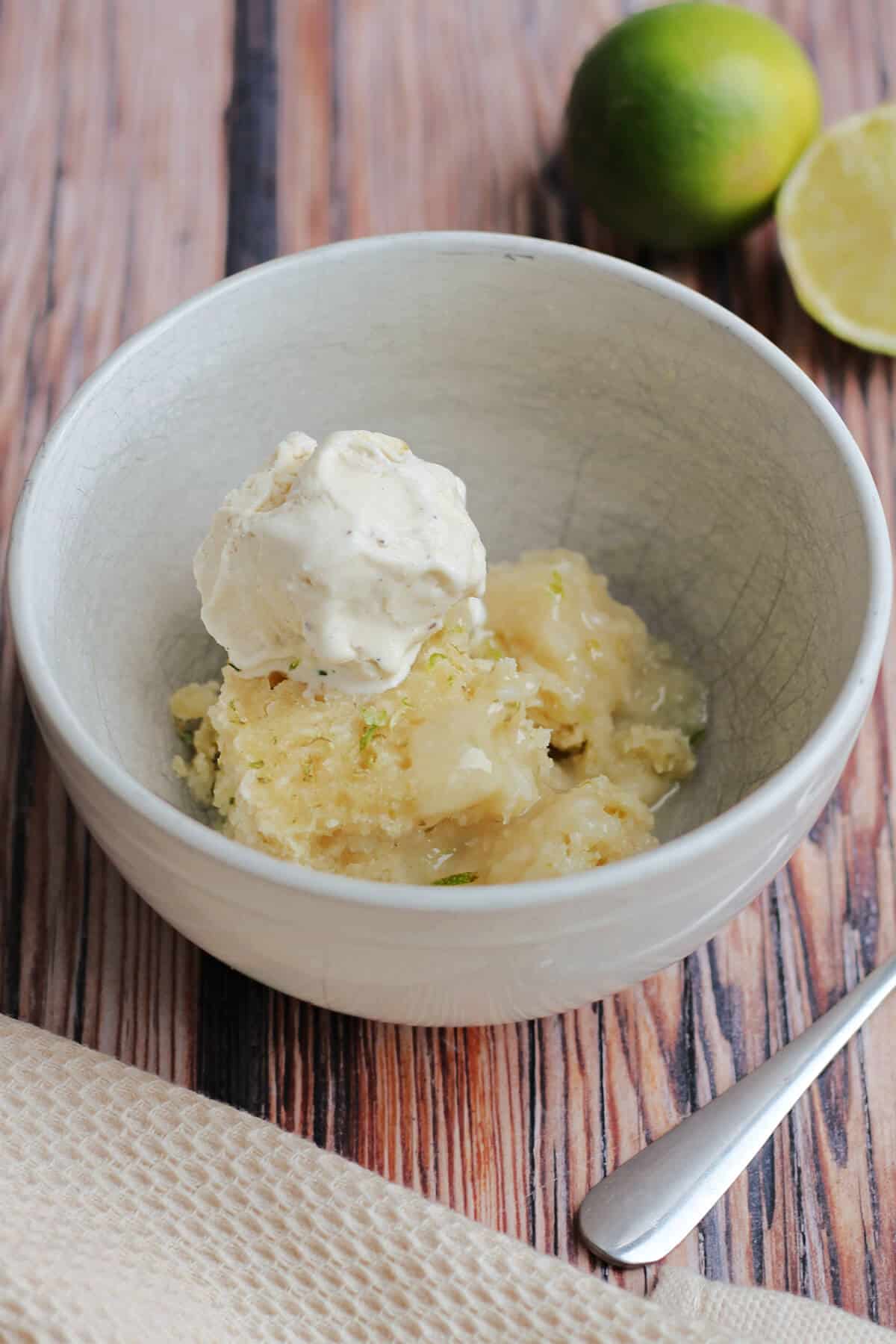 Bowl of coconut lime sponge with lime sauce, with ice cream on top.