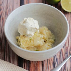 Bowl of coconut lime sponge with lime sauce, with ice cream on top.