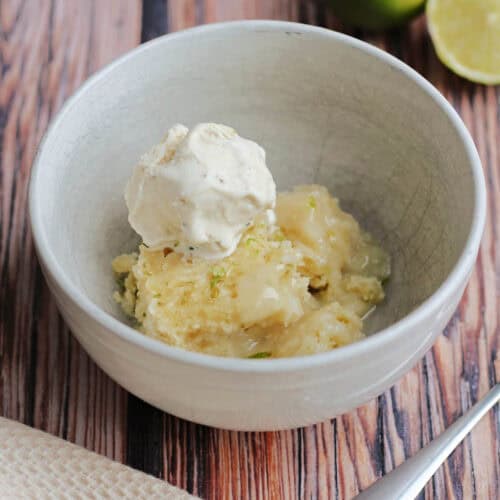 Bowl of coconut lime sponge with lime sauce, with ice cream on top.