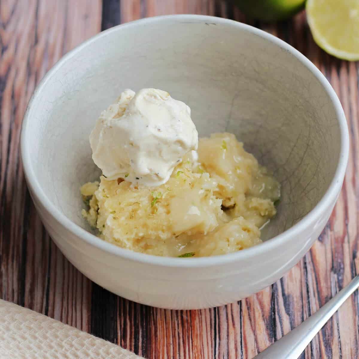 Bowl of coconut lime sponge with lime sauce, with ice cream on top.