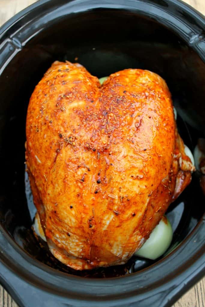 Turkey breast rubbed with spices in slow cooker pot.