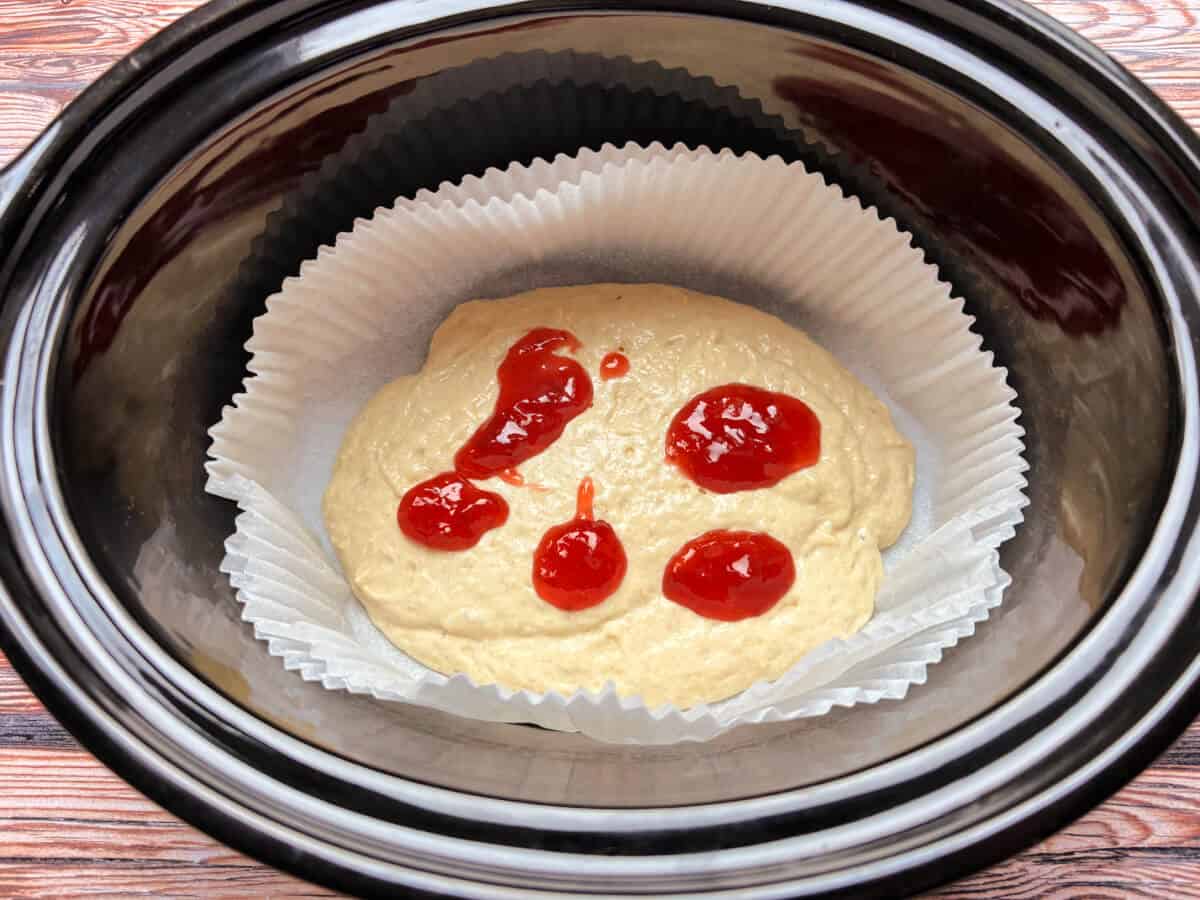 Cake mixture topped with spoonfuls of jam.