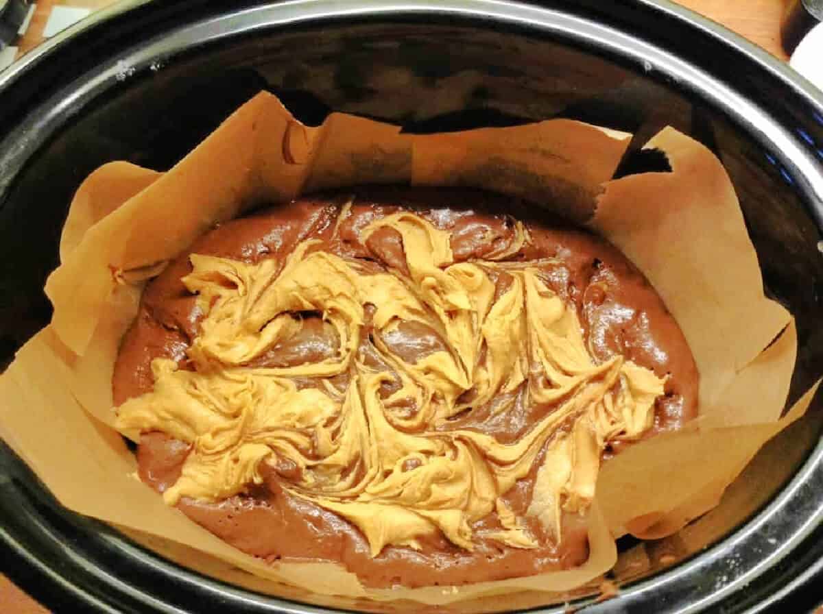 Brownies with peanut swirl marbled through in slow cooker pot.