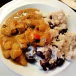 Caribbean chicken curry with rice and peas on a white plate.
