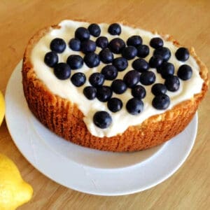 Cake with icing and blueberries on top on a white plate.