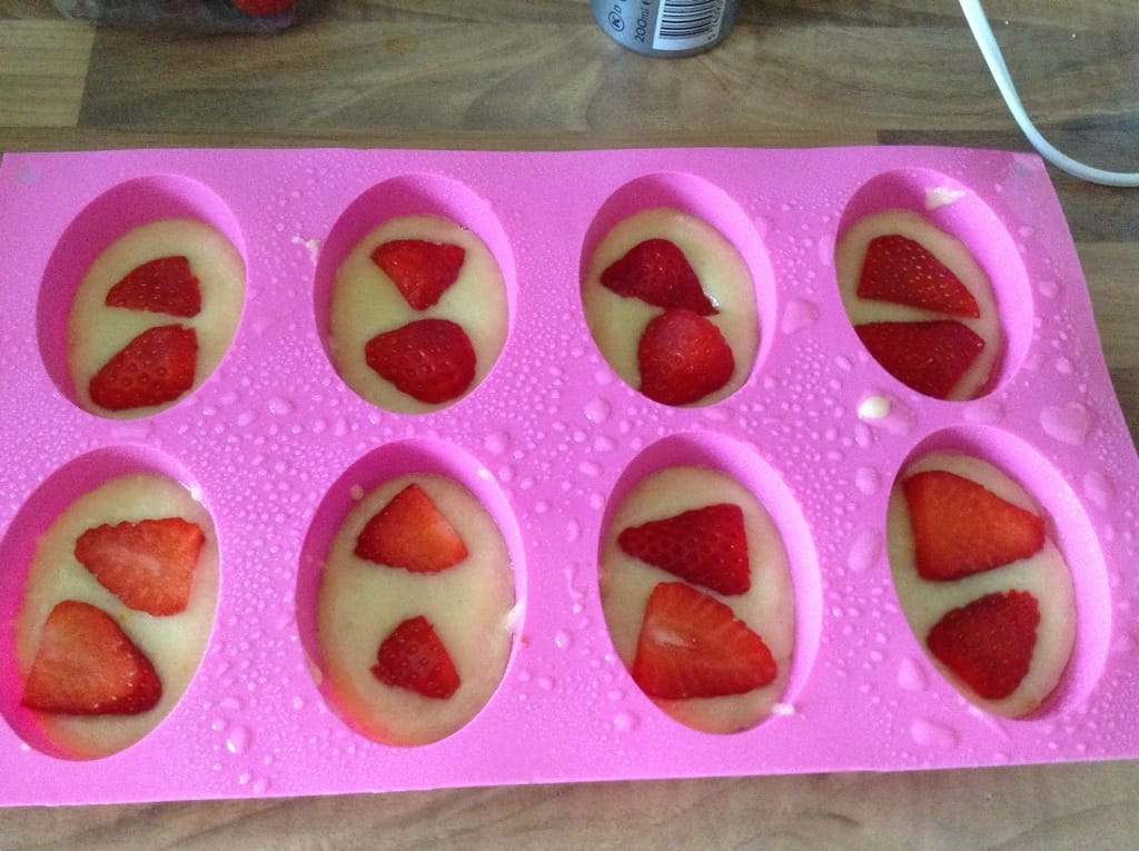 Friand tray with mixture topped with strawberries.