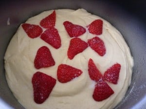 Cake mixture with strawberries on top, in cake tin.