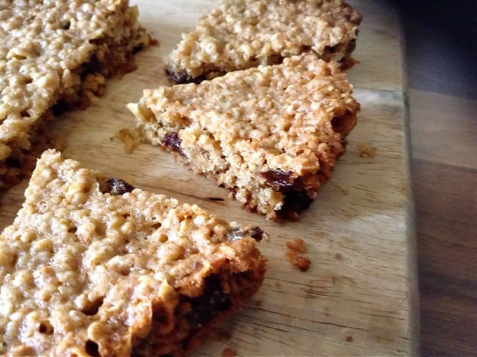 Close up of slices of oat bars on a wooden chopping board.