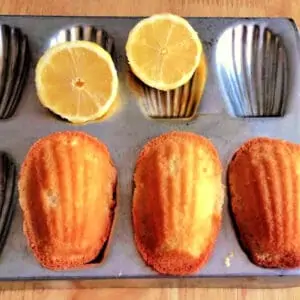 Madeleine cakes in a madeleine tin, with lemon halves.