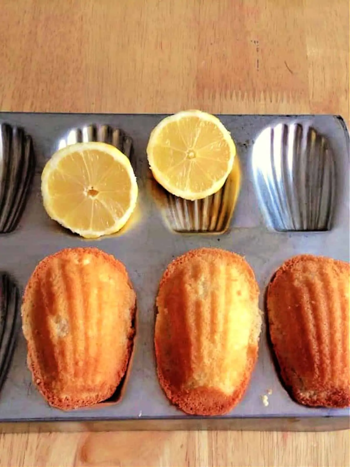 Madeleine cakes in a Madeleine tin, with lemon halves.