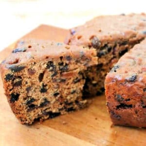 Slice of fruit cake cut out from round cake on wooden board.