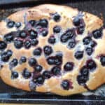 Focaccia bread topped with blackcurrants and sprinkled sugar.