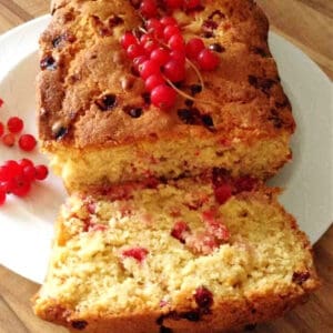 Close up of a sliced redcurrant loaf cake, showing the fruit inside.