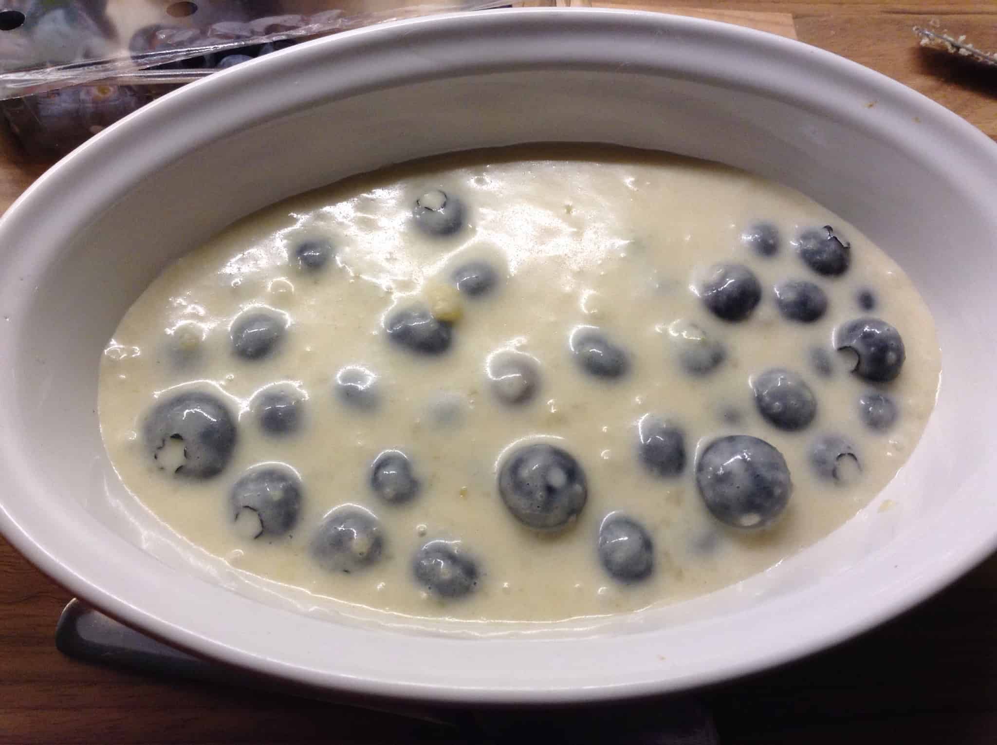 Sponge mixture with blueberries in oval dish.