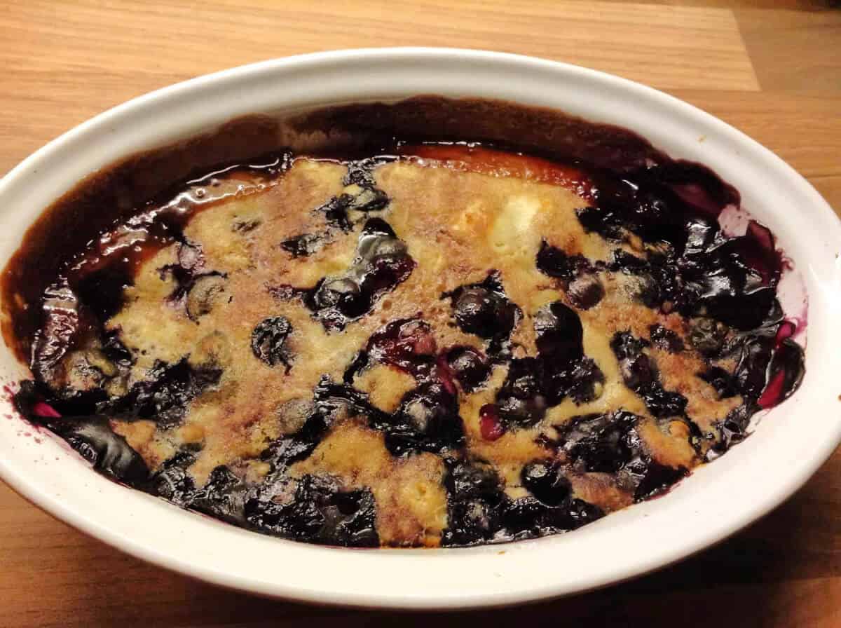 Oval dish with blueberry sponge pudding.