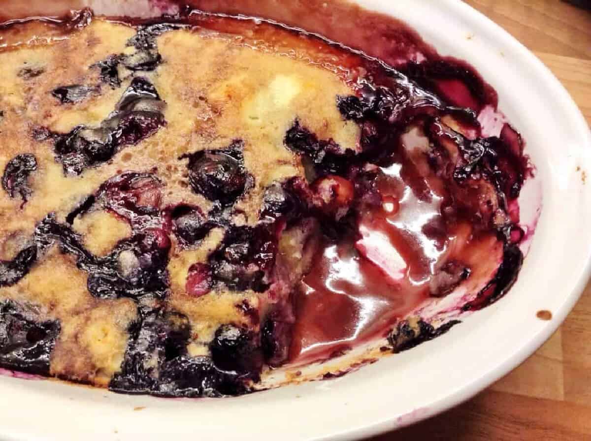 Oval serving dish with blueberry self-saucing pudding, showing the sauce underneath.