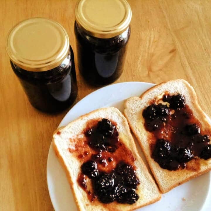 Two jars of jam and two slices of toast with jam, on white plate.