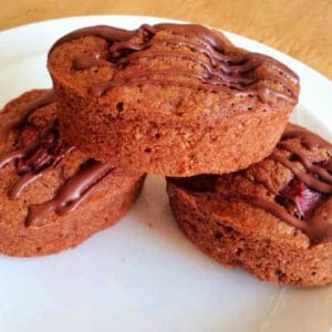 Chocolate friands with drizzled chocolate on a white plate.