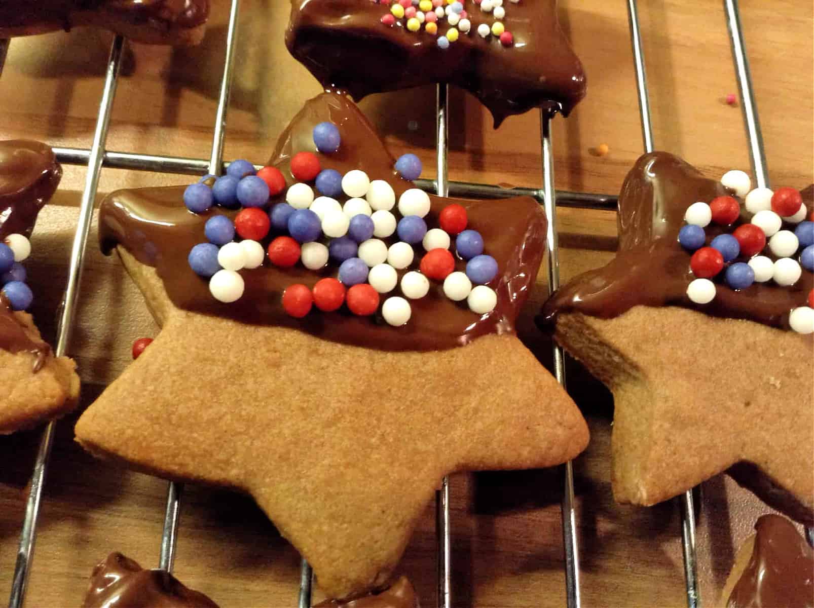 Close up of star shaped chocolate cookies with half chocolate covering and sprinkle decoration.