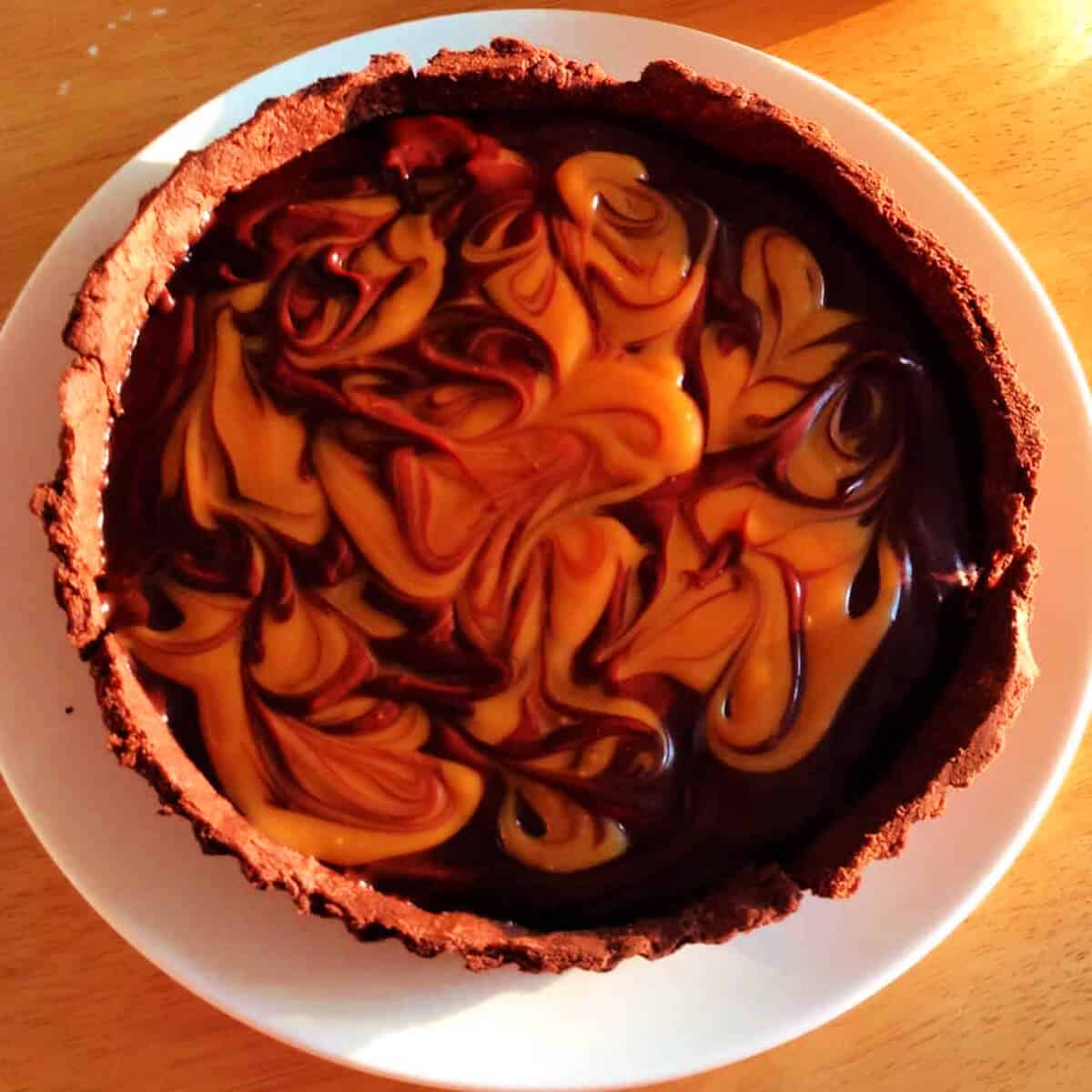 Chocolate salted caramel swirl tart on a white plate.