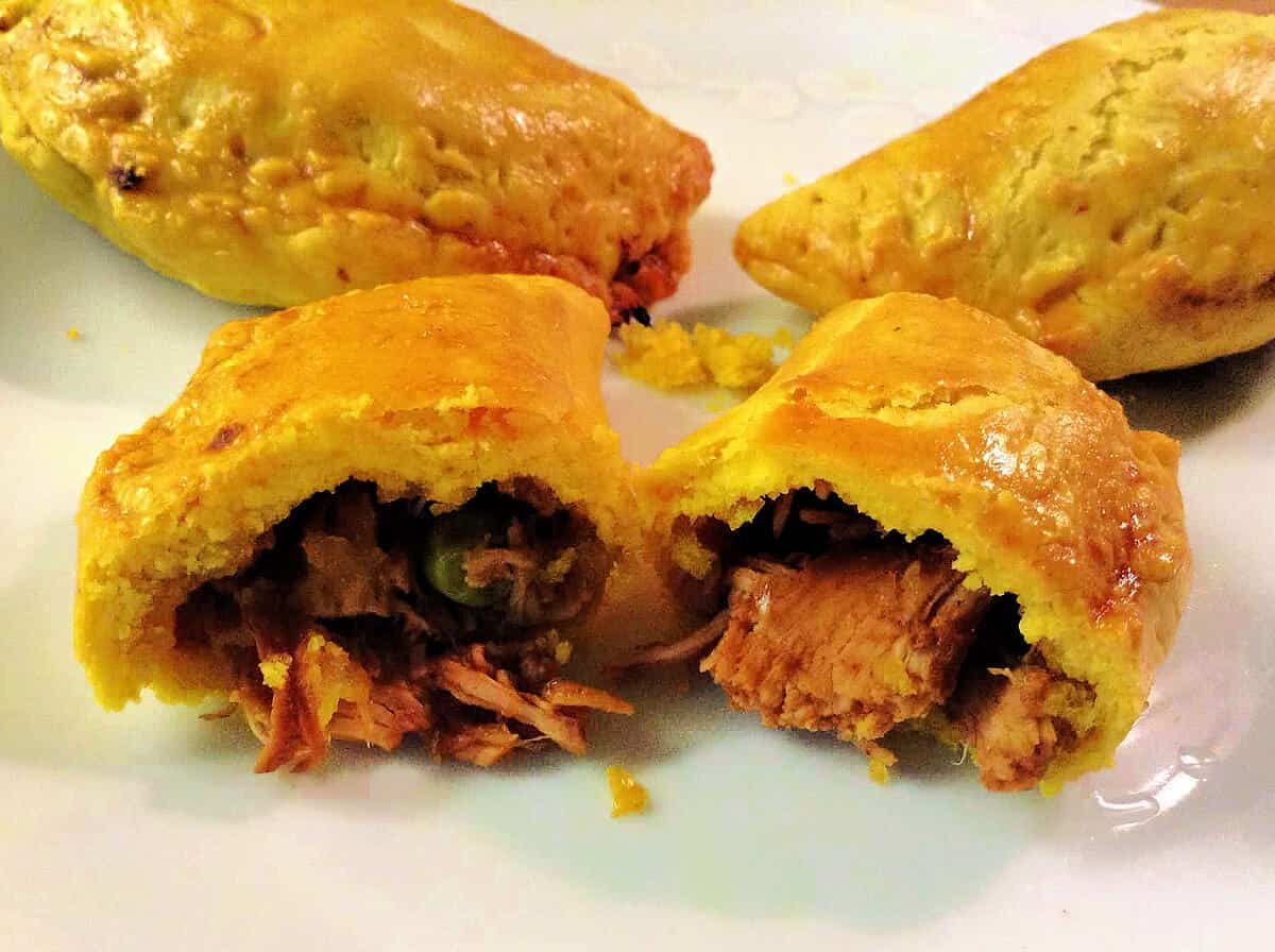 Patties on a white plate, with one torn in half showing the filling.