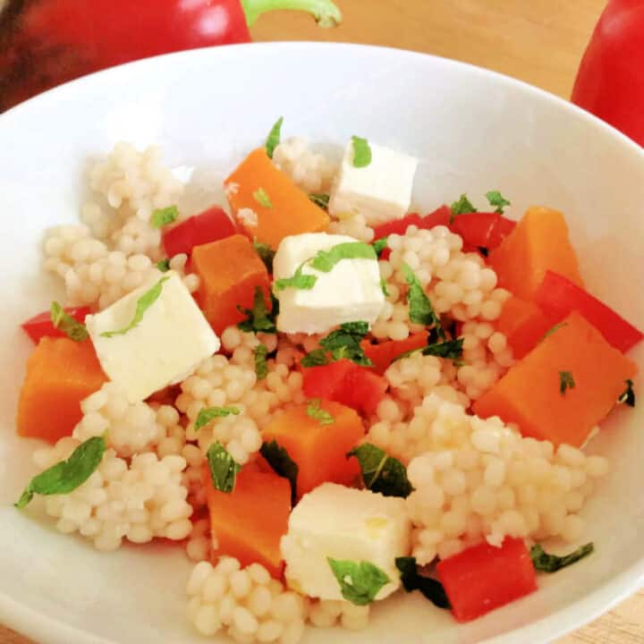 White bowl of salad with couscous, feta and butternut squash.