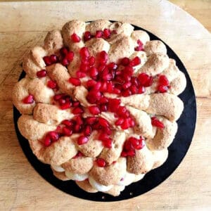 View from above of pistachio dacqquoise dessert topped with pomegranate seeds.