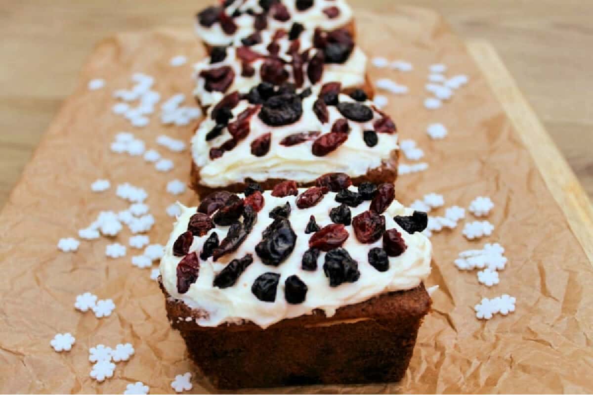 Close up of small loaf cakes with buttercream topping and dried berries on top.