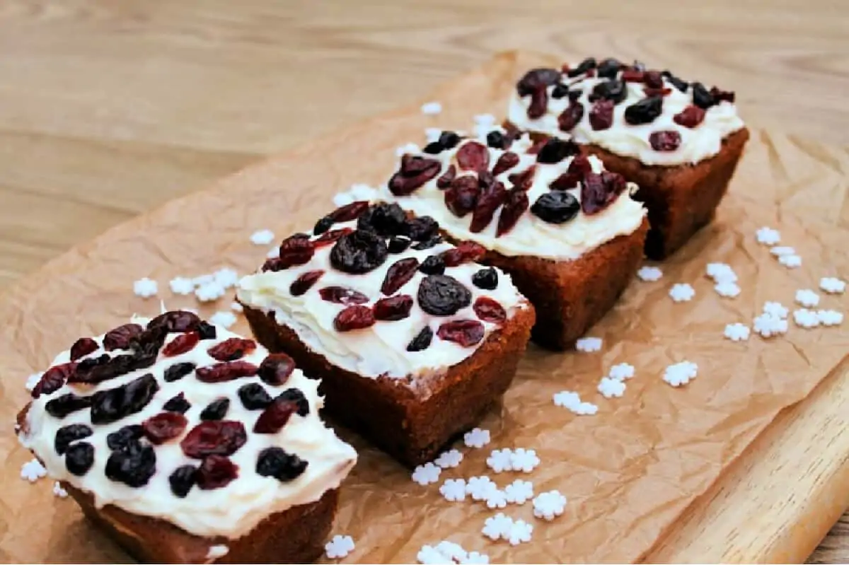 A row of four mini ginger loaf cakes on a wooden board.