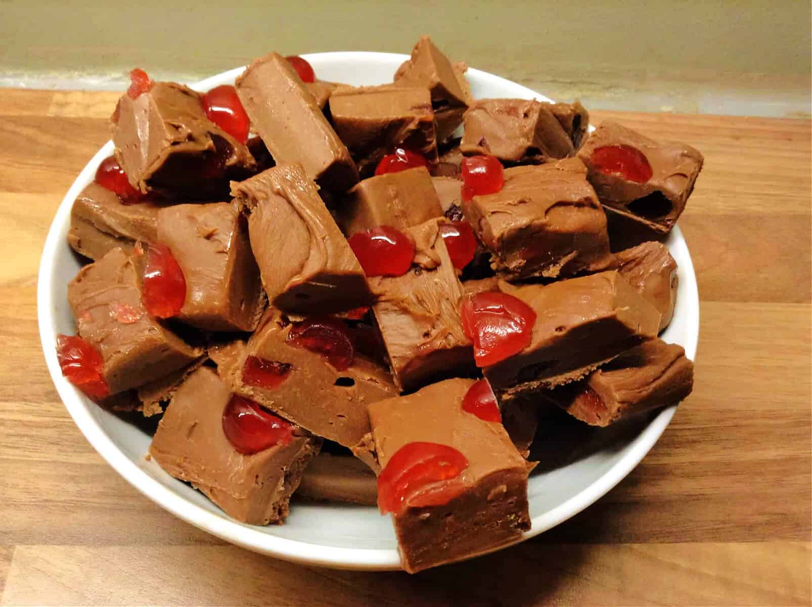 White plate with chopped up squares of chocolate cherry fudge.