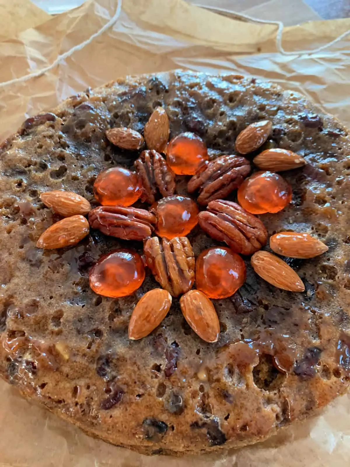 Close up of top of fruit cake decorated with nuts and cherries.