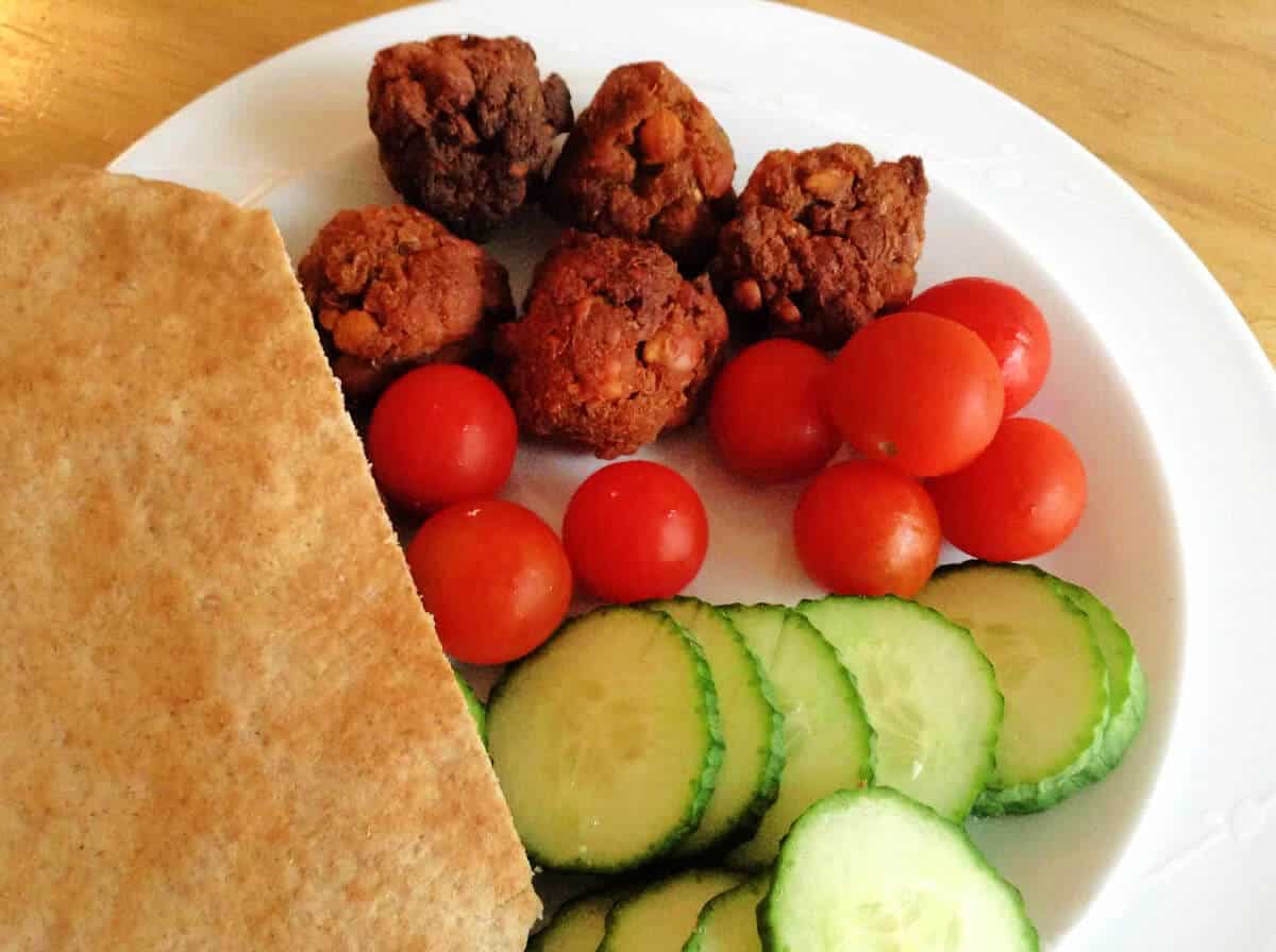 Falafel with salad and pitta bread on a white plate.