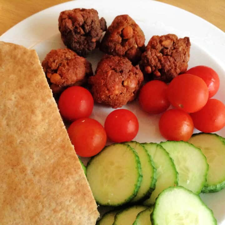 Falafel with salad and pitta bread on a white plate.