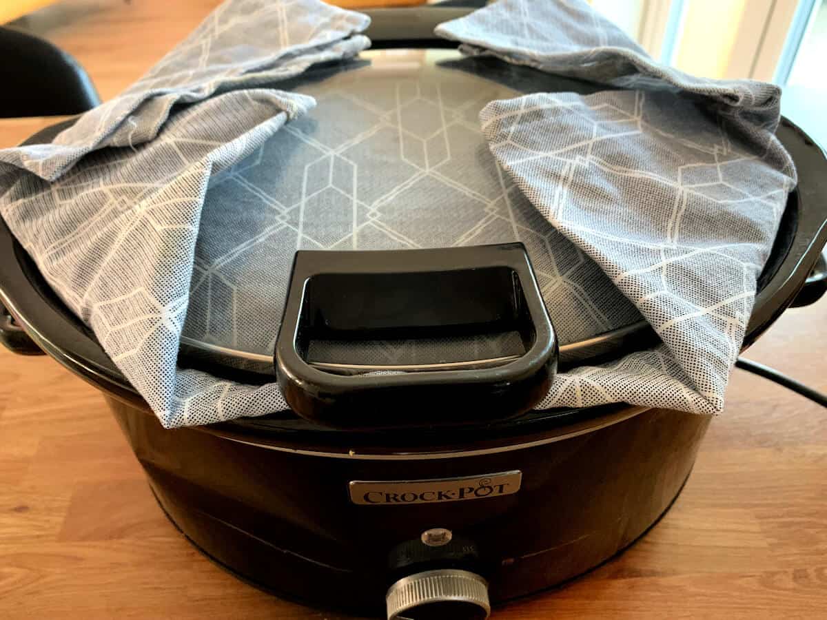 Slow cooker with tea towel under the lid.
