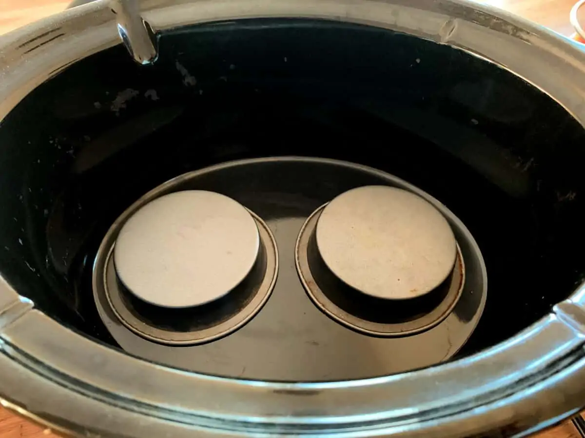 Slow cooker pot with two small upturned cake tins at the base.