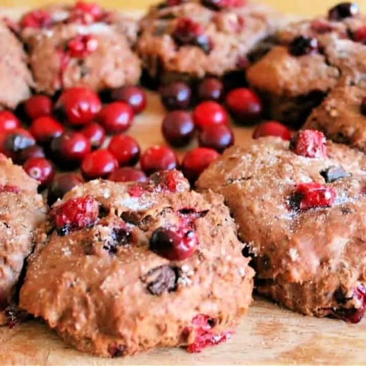 Chocolate scones with cranberries on a wooden board, with fresh cranberries.