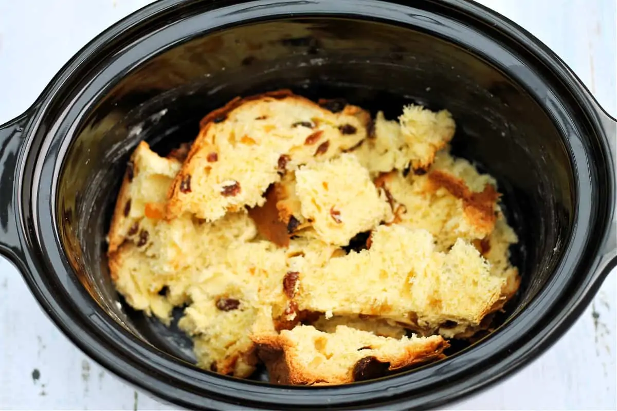 A layer of panettone pieces in a slow cooker pot.