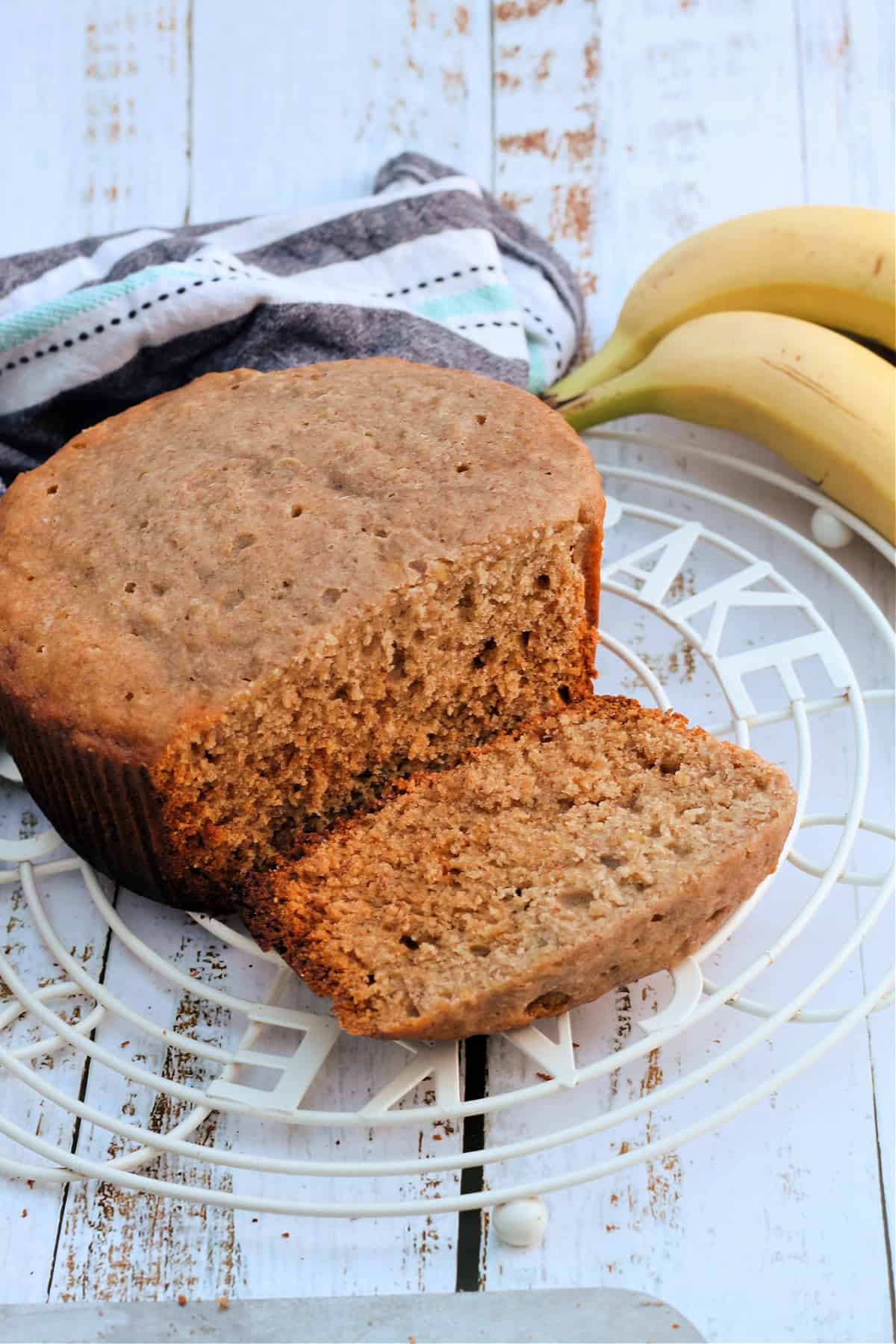 Banana bread on a cooling rack, one slice cut ready to eat.