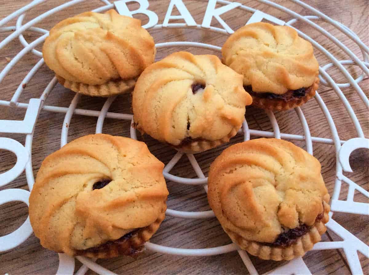 Mince pies with Viennese whirl topping on cooling rack,