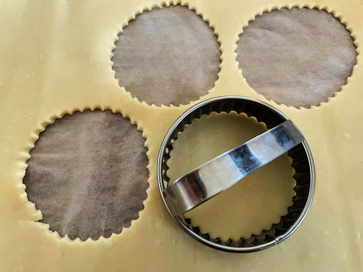 Cutting rounds out of pastry with a fluted cutter.