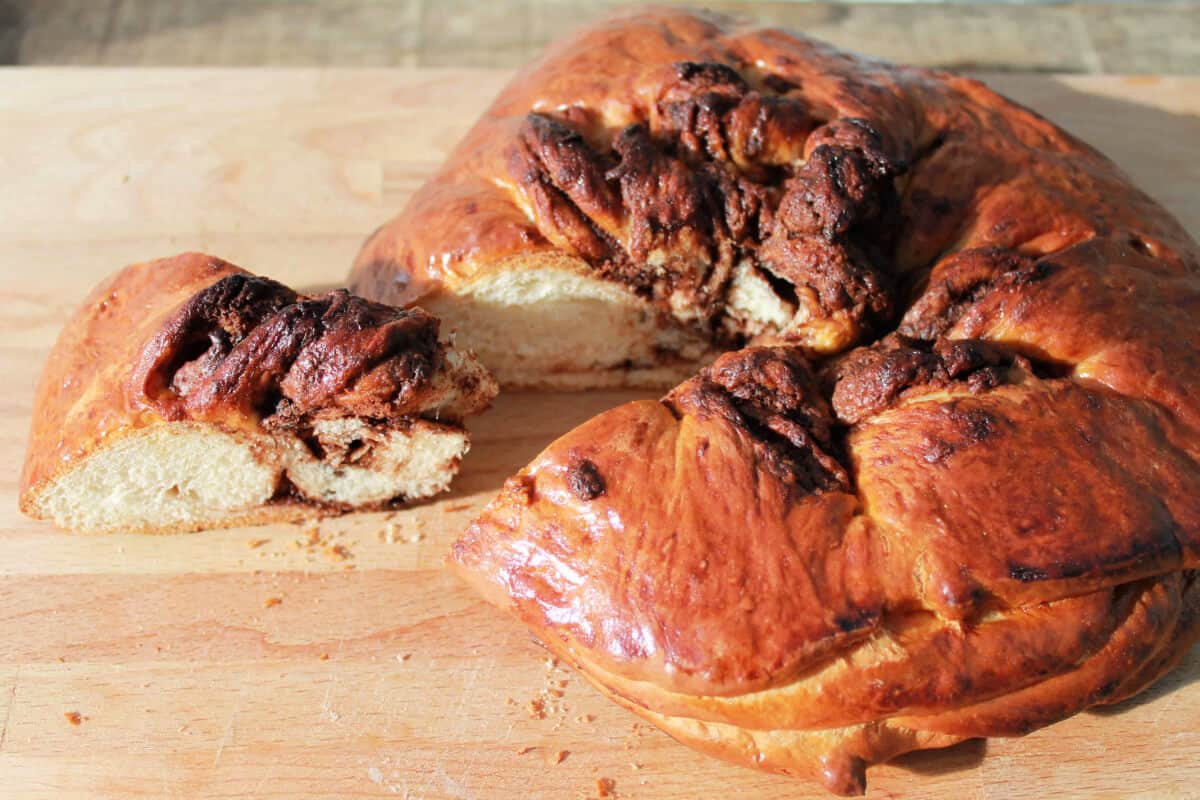 Nutella bread with a slice cut out, on wooden board.