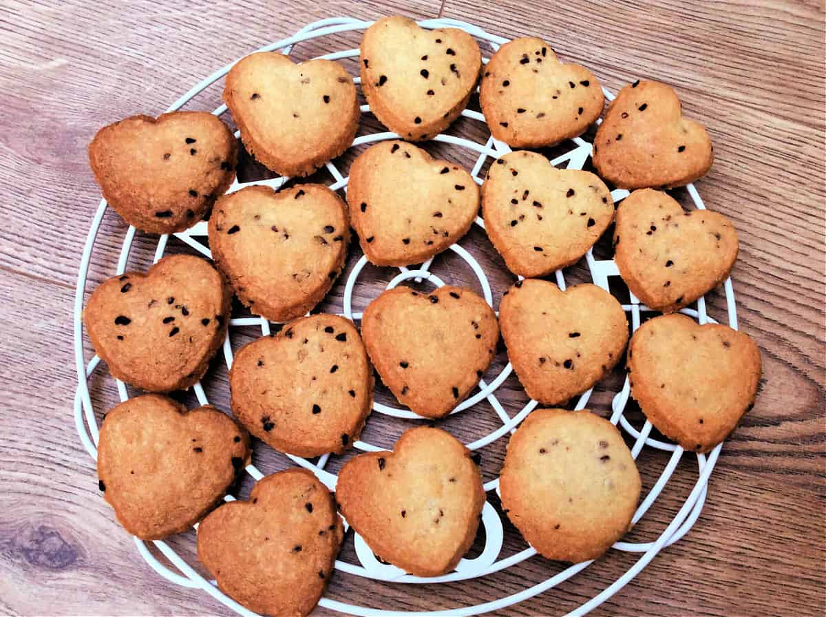 Raspberry shortbread hearts on a white cooling rack.