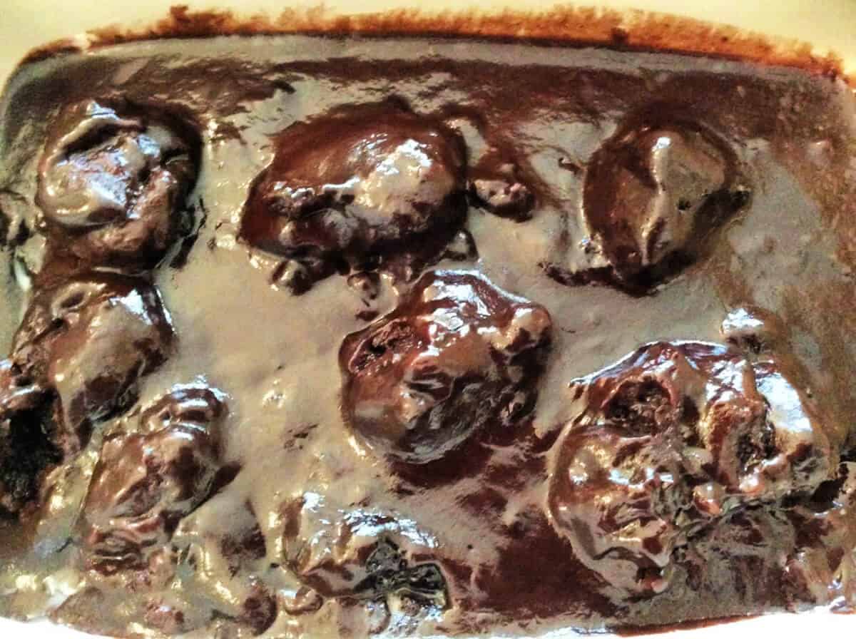 Dumplings in chocolate sauce in a serving dish.