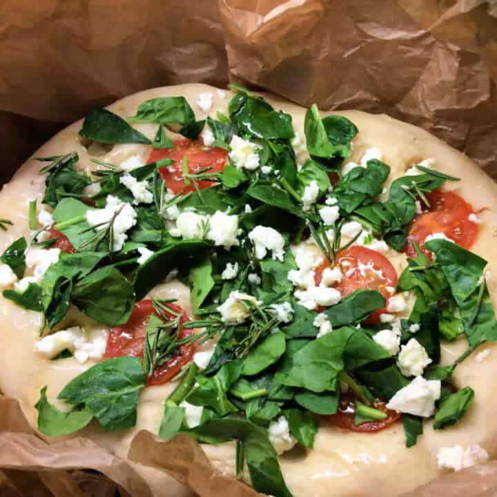 Focaccia with spinach and feta topping on baking paper.